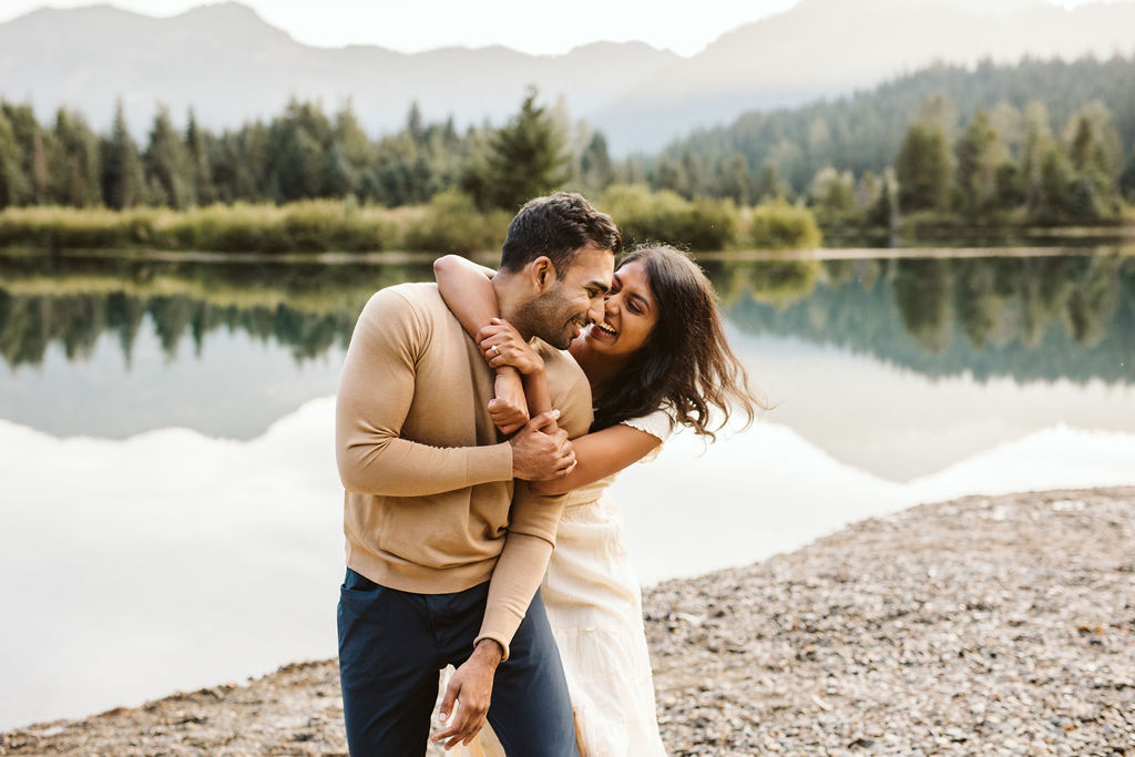 girl hugs boy from behind and they smile at each other during gold creek pond engagement