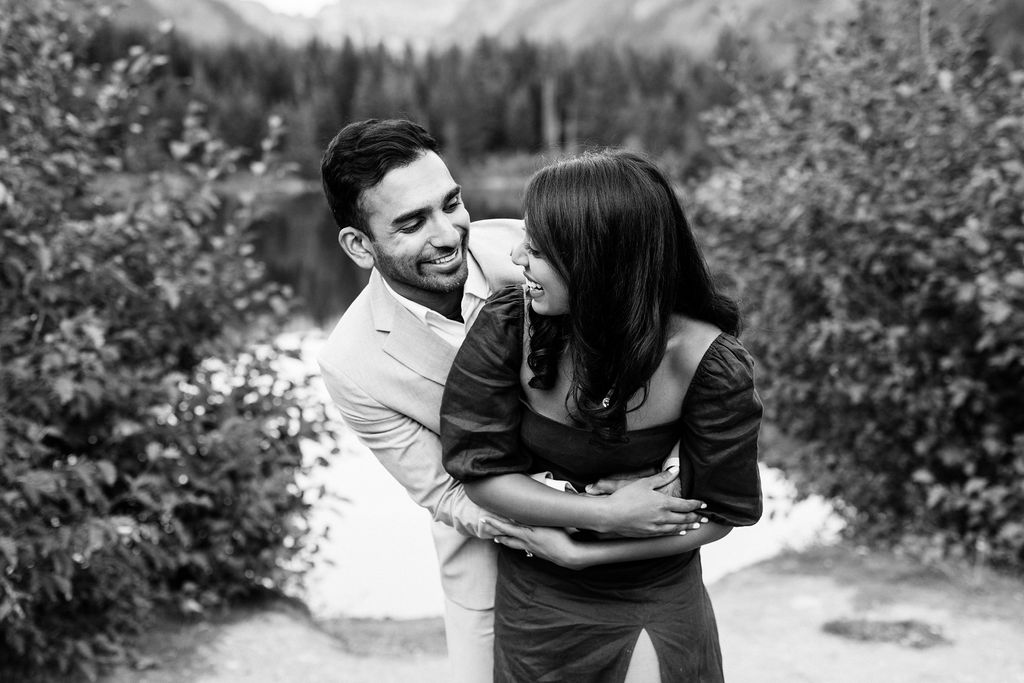 boy hugs girl from behind and the smile at each other at Gold Creek Pond engagement session
