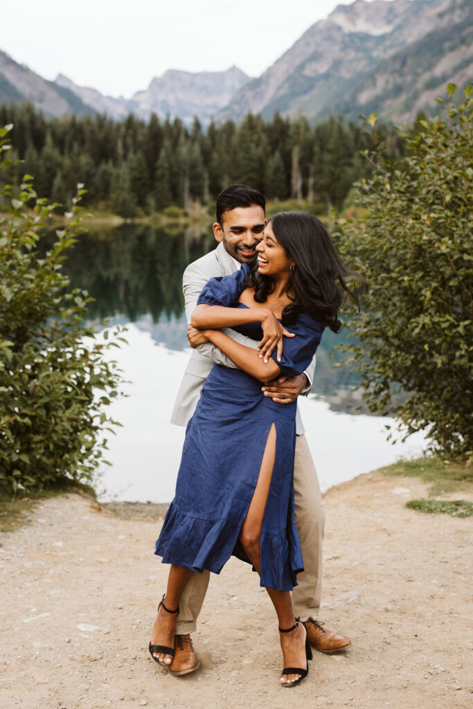 boy hugs girl from behind and the smile at each other at Gold Creek Pond engagement session