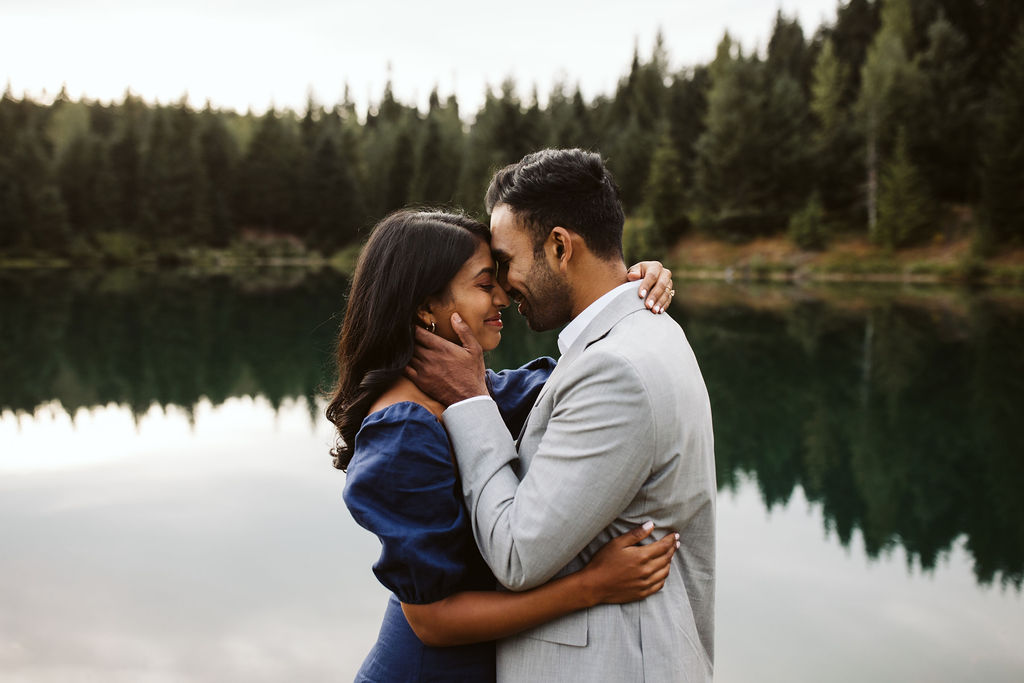 man and woman hold each other in front of lake during Gold Creek Pond engagement session
