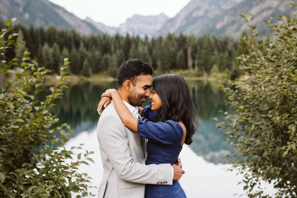 man and woman hold each other in front of lake