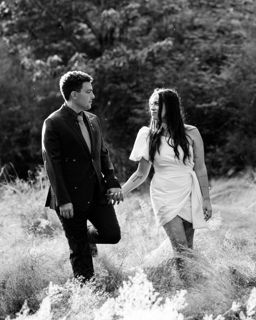 bride and groom walk through field together