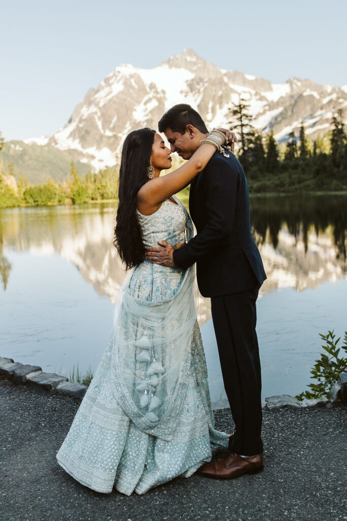 boy and girl face each other in front of a lake during mt baker engagement photos