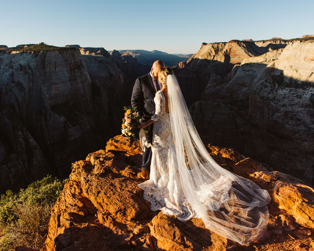 bride and groom kiss on cliffside during elopement