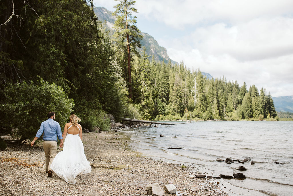 bride and groom walk beside lake wenatchee
