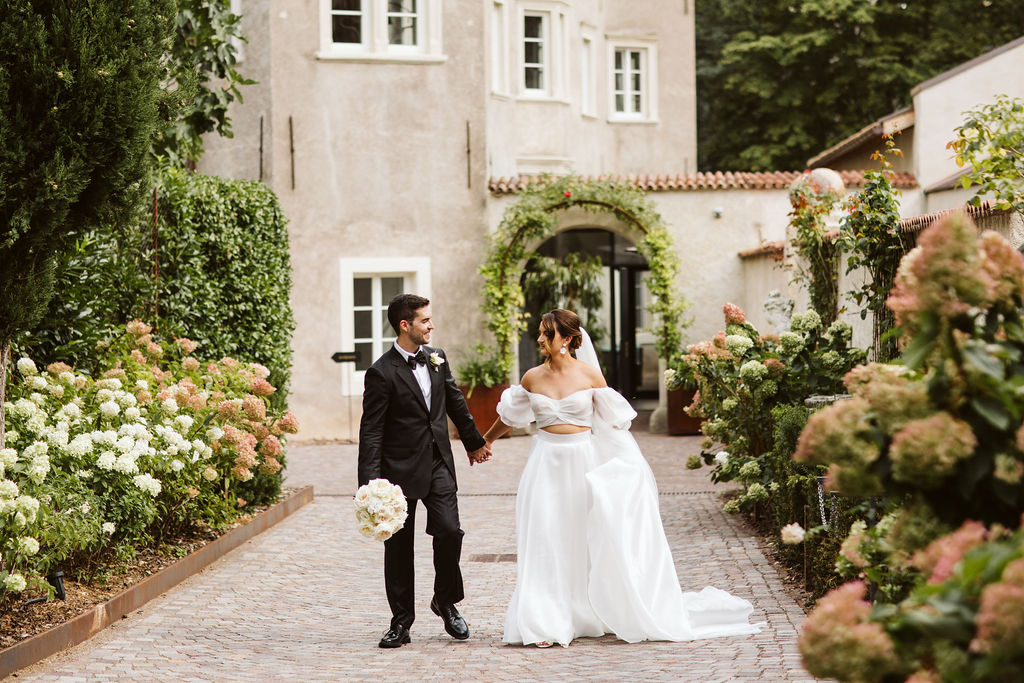 bride and groom walk down cobble stone path holding hands