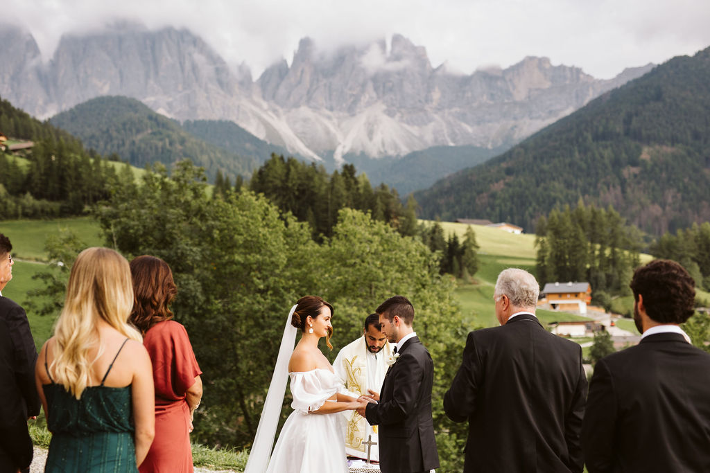 bride and groom hold hands during ceremony at dolomites