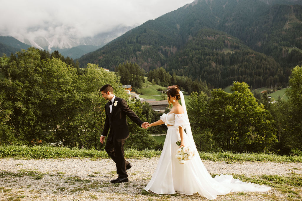 bride and groom walk together with lush greenery in the background