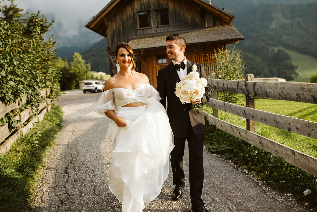bride and groom walk down path together with house in the background