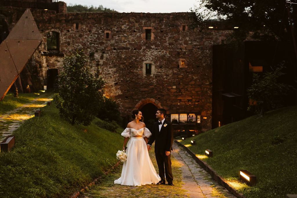 bride and groom stand together in front of a castle