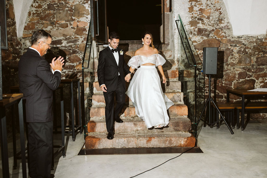 bride and groom walk down stairs into their reception
