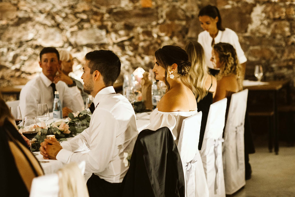 bride and groom sit at long table with guests