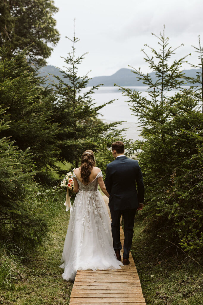 bride and groom walk through trees together