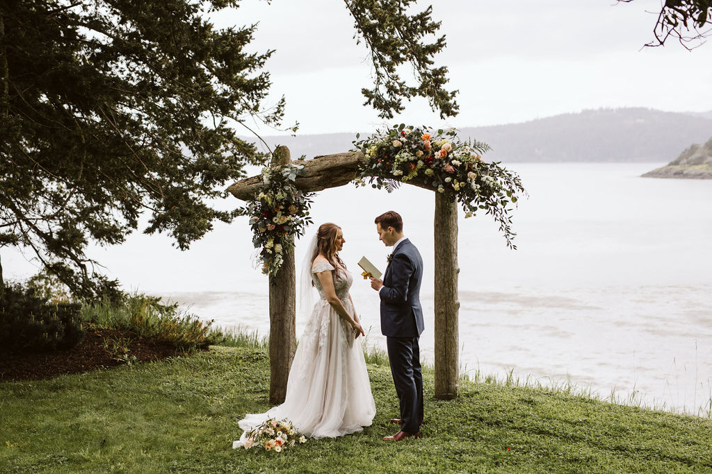 bride and groom share private vows under a floral alter