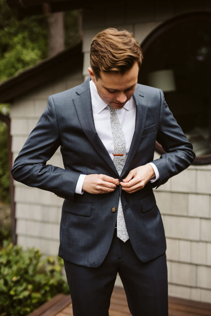 groom looks down at himself while he puts on suit jacket