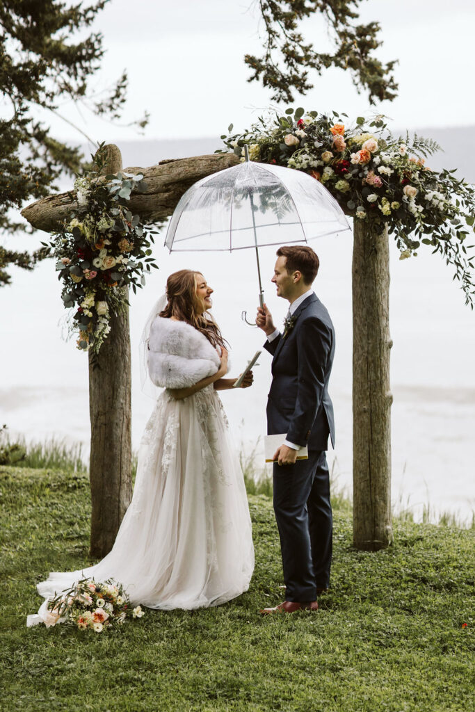 groom holds clear umbrella over bride during ceremony on orcas island