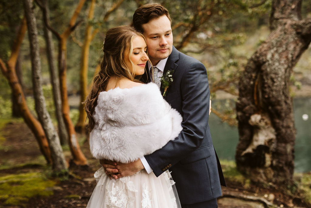 bride and groom hold each other close with red wood trees in the background