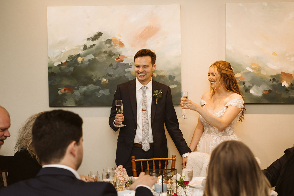 bride and groom hold up glasses in a toast