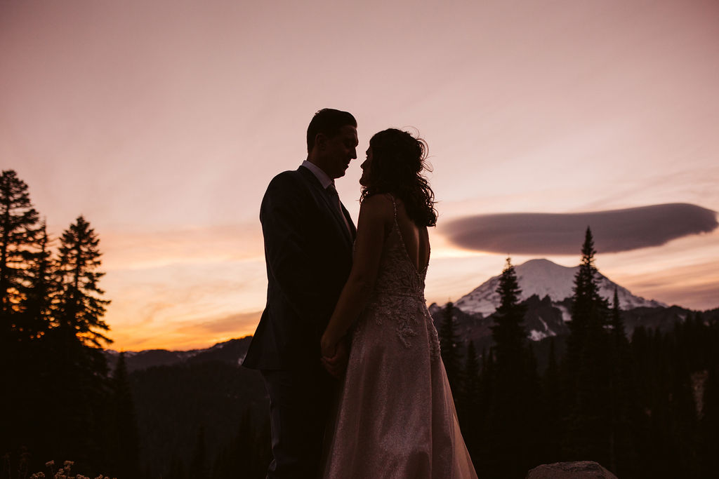 bride and groom stand at sunset at mt rainier