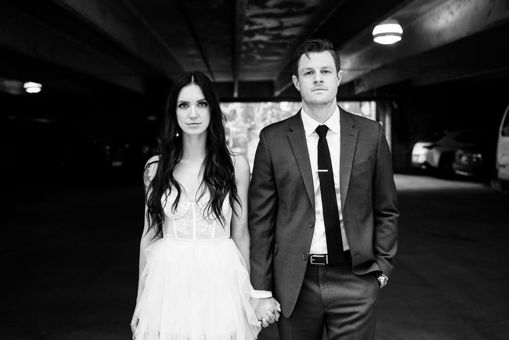 bride and groom stand in parking garage during modern city elopement