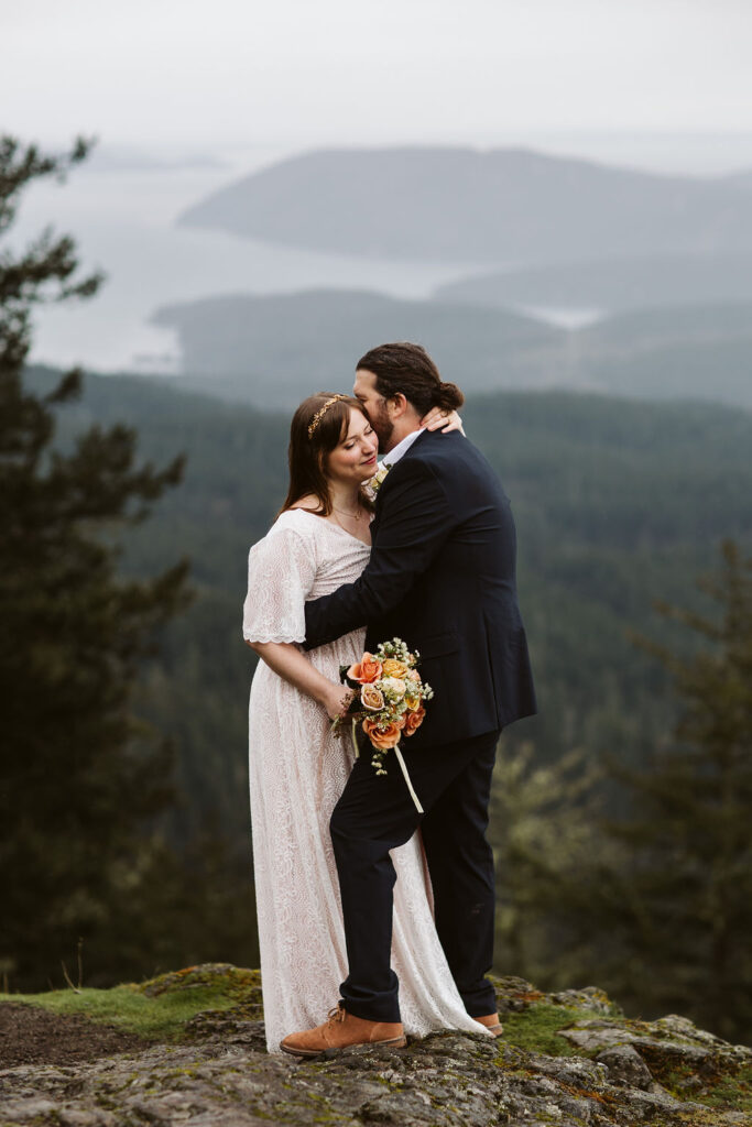 bride and groom embrace on top of mountain at pacific northwest elopement