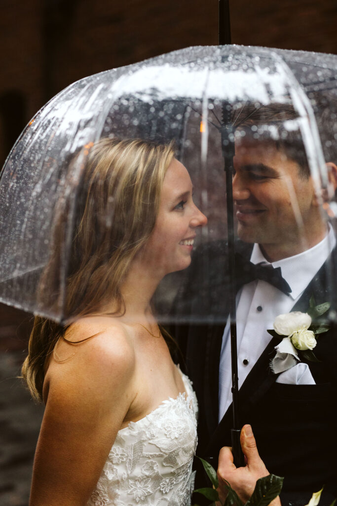 bride and groom smile at each other under clear umbrella during pacific northwest elopement
