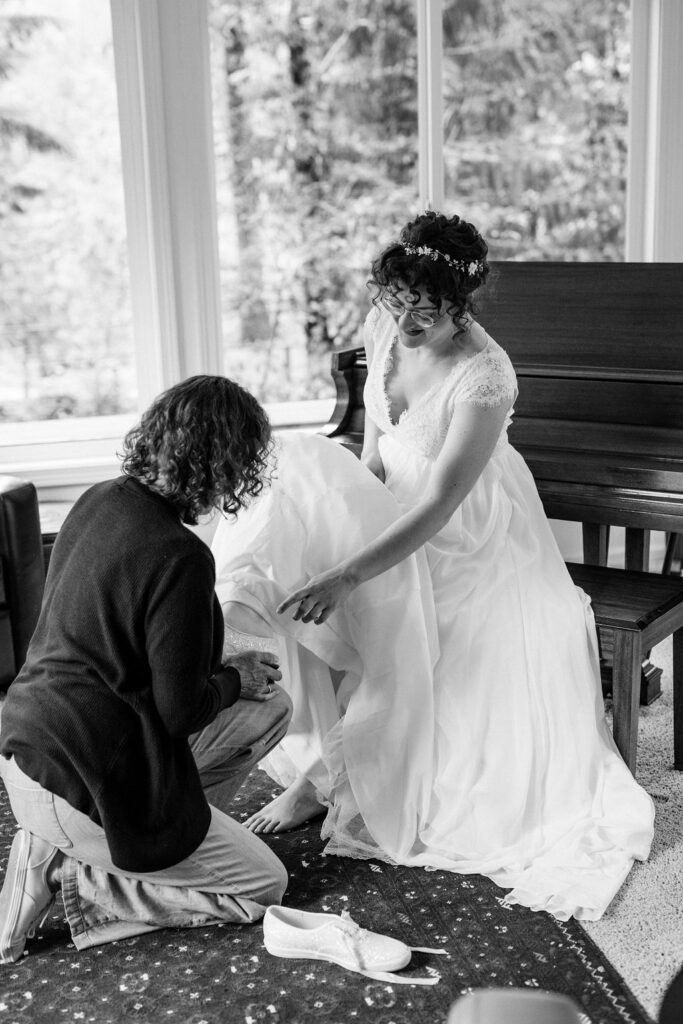 bride has her shoes put on by an older woman