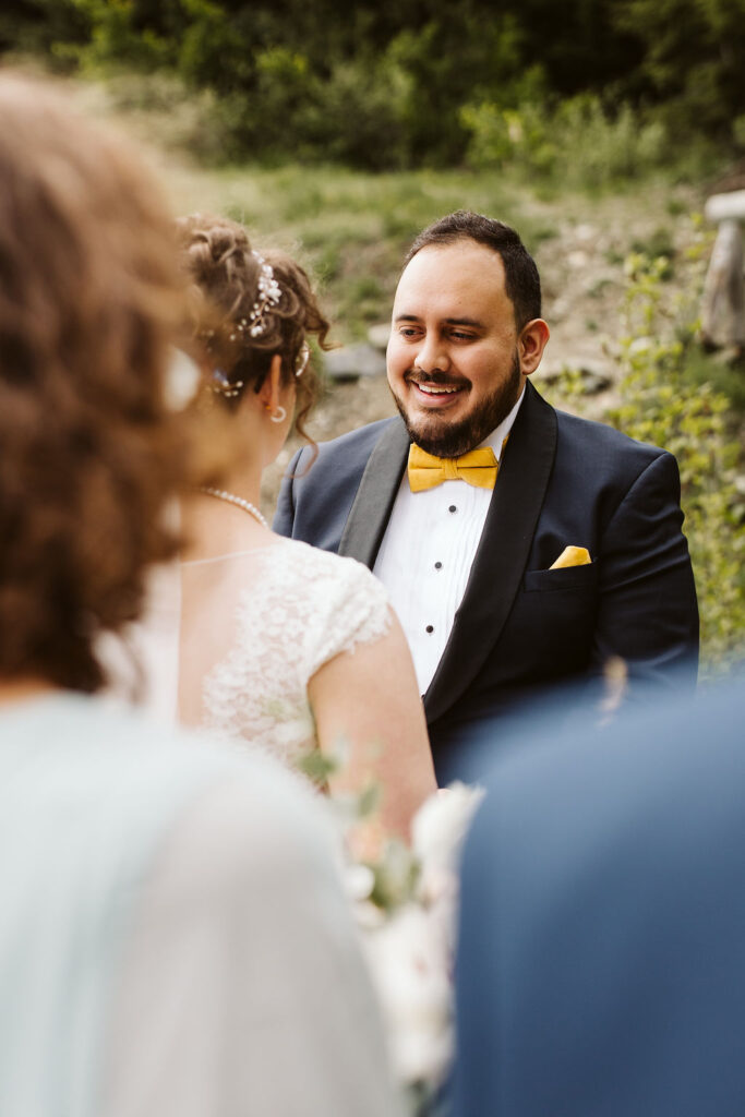 groom smiles at bride during ceremony