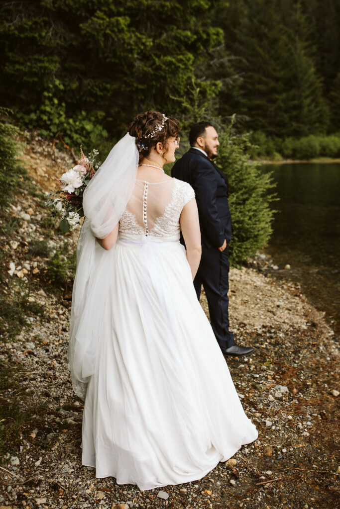 back of brides dress as she walks along lake