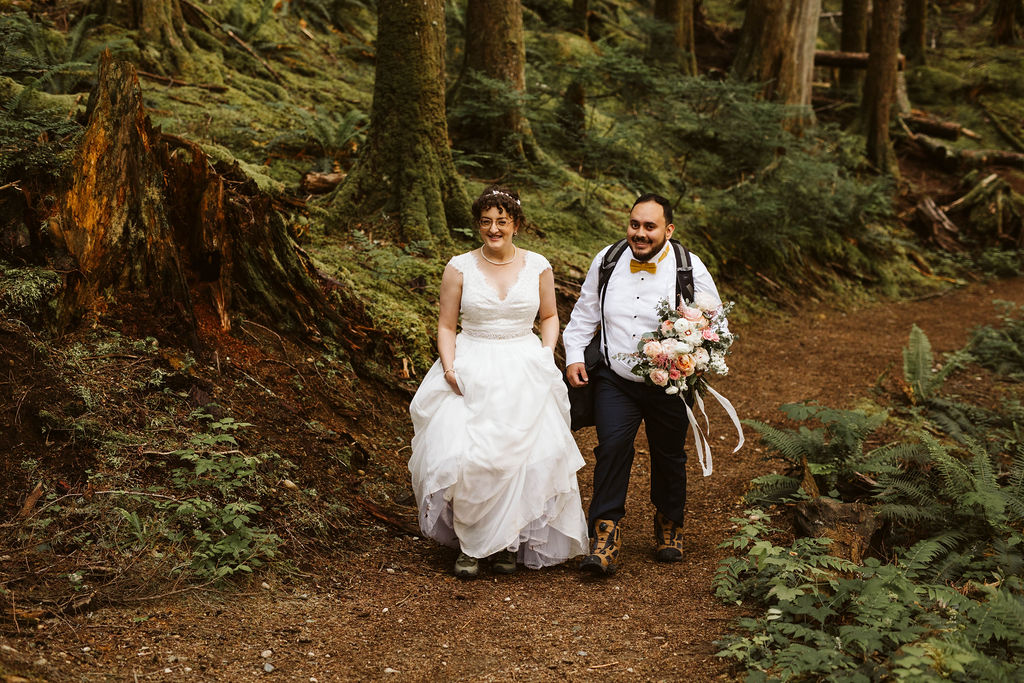 bride and groom hike up a trail 