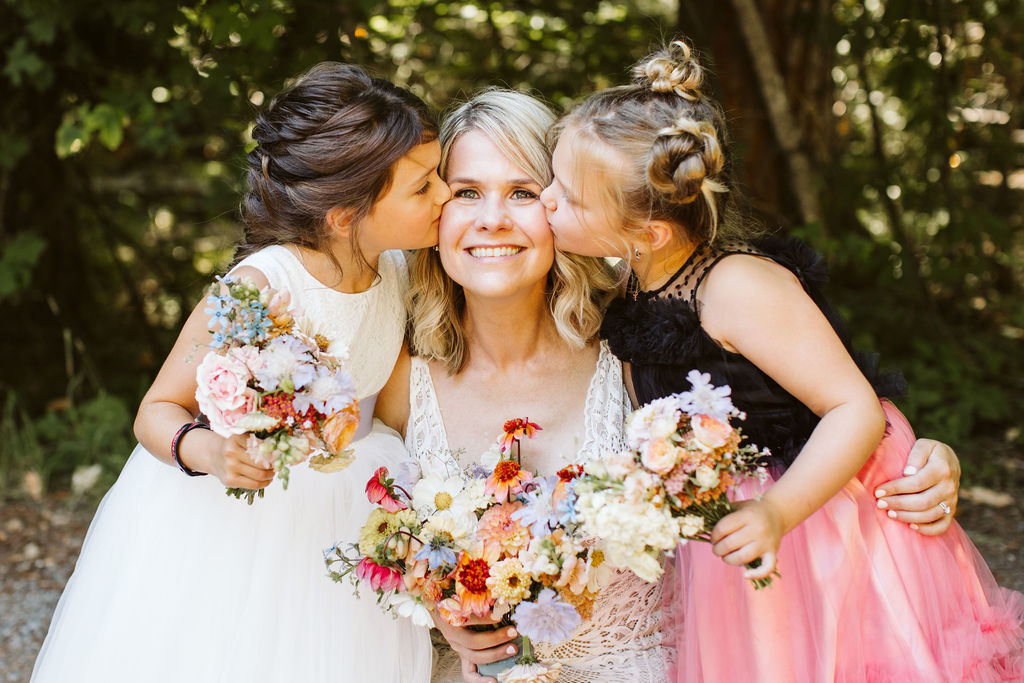 two little girls kiss the bride on either cheek