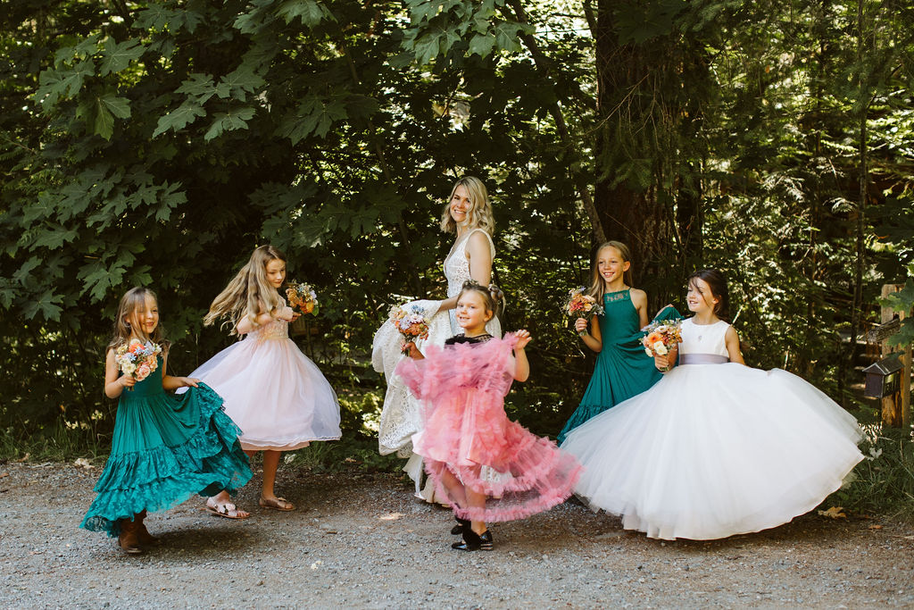 several little girls all twirl in their dress around the bride