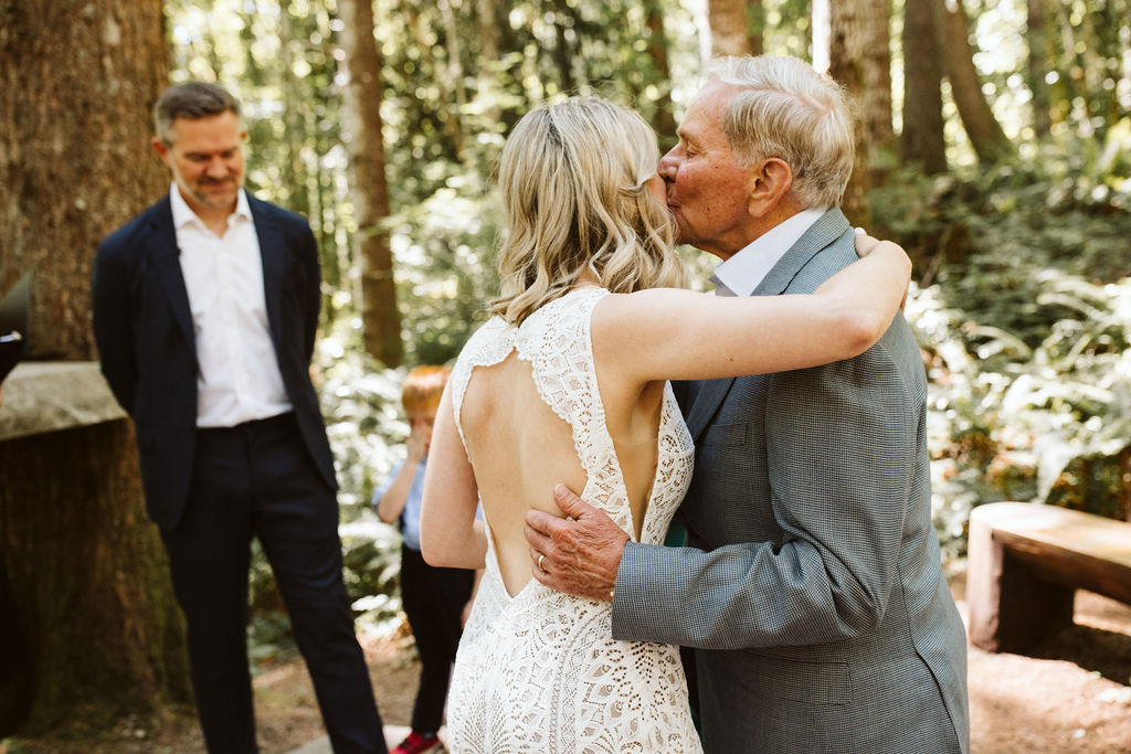 older man kisses bride on forehead during ceremony