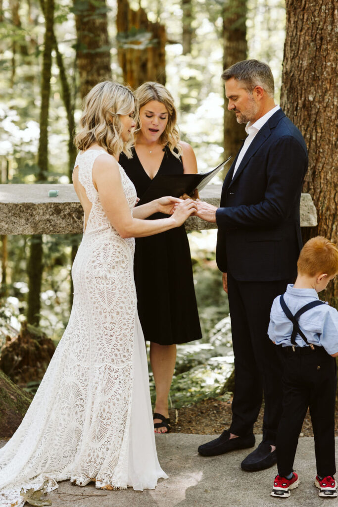 bride puts ring on groom during ceremony in the woods