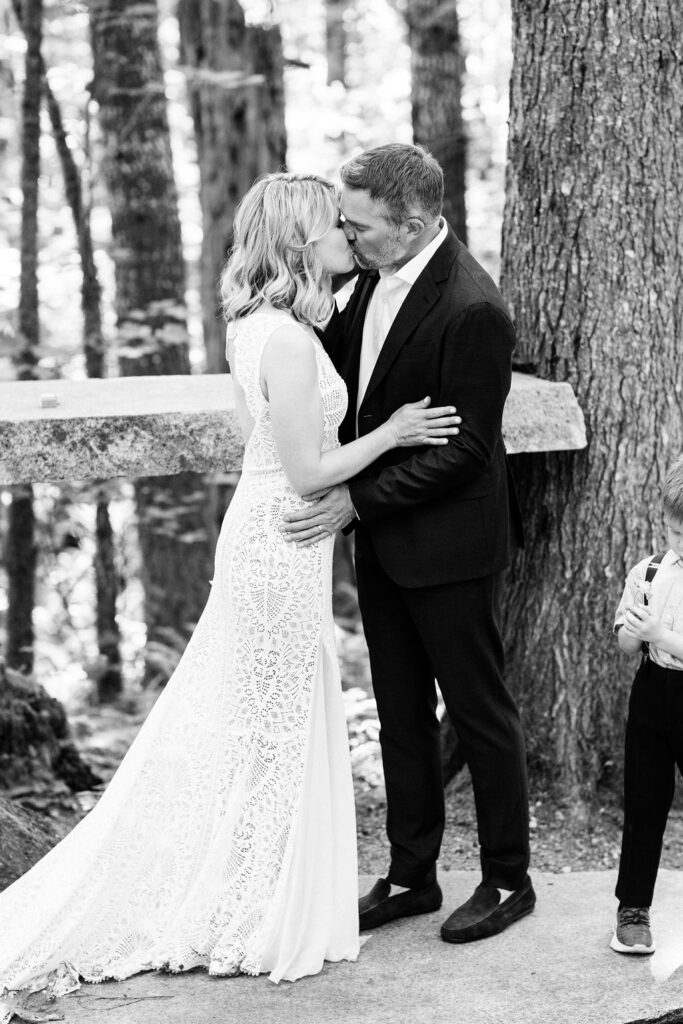 bride and groom kiss in the woods during ceremony