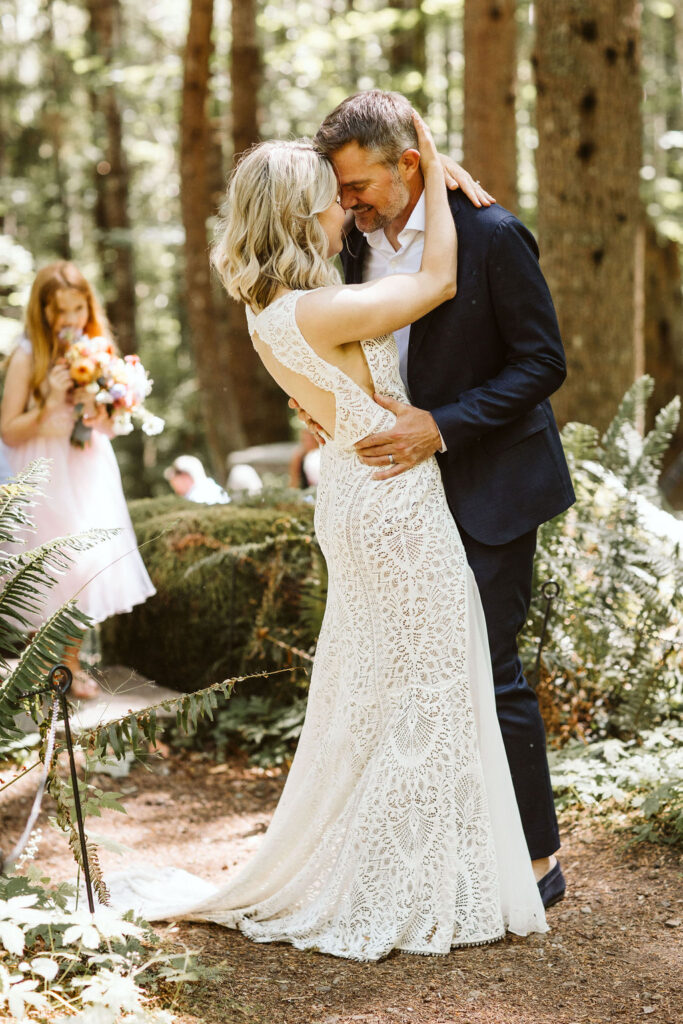 bride and groom press their foreheads together in middle of woods