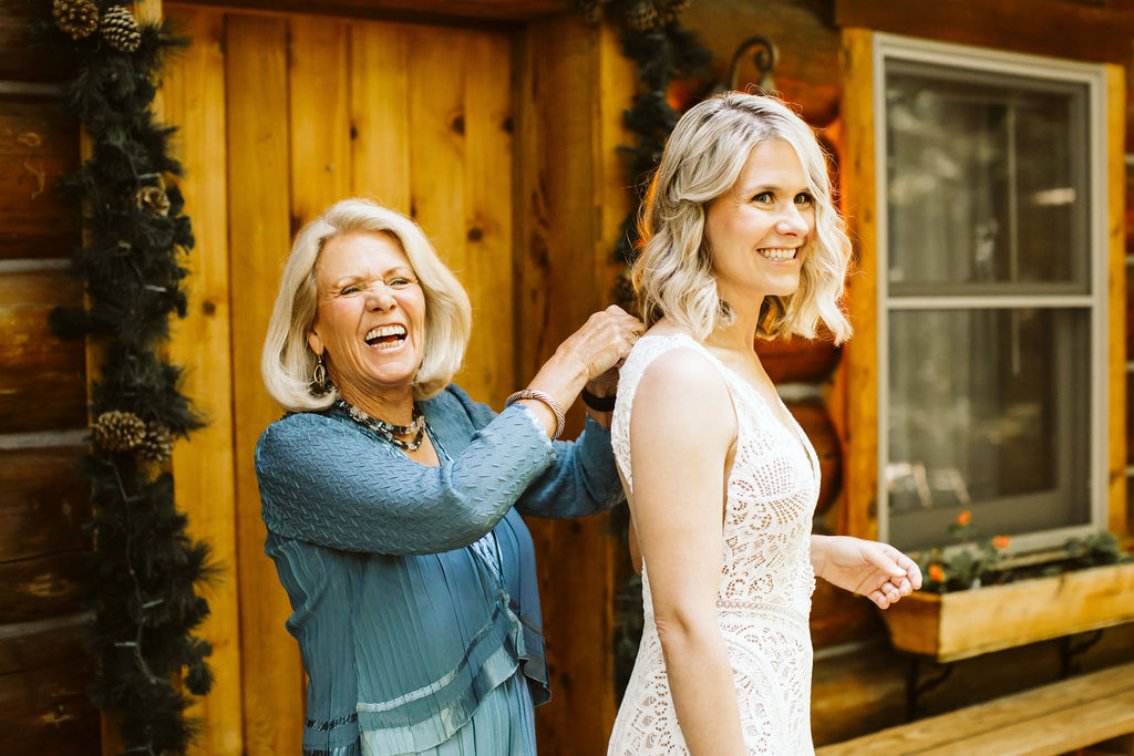 older woman helps bride put on dress