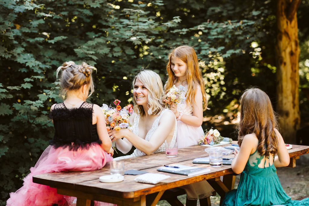 bride holds out wildflower bouquet to little girl
