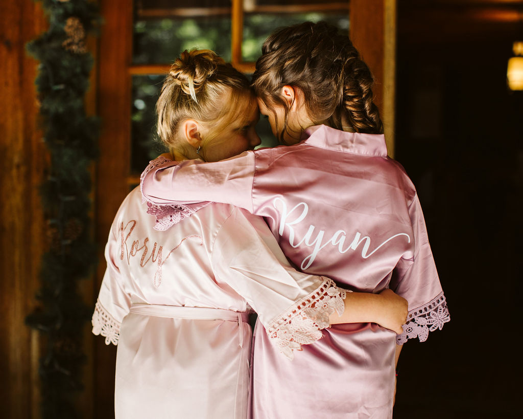 two little girls in pink robes hug each other