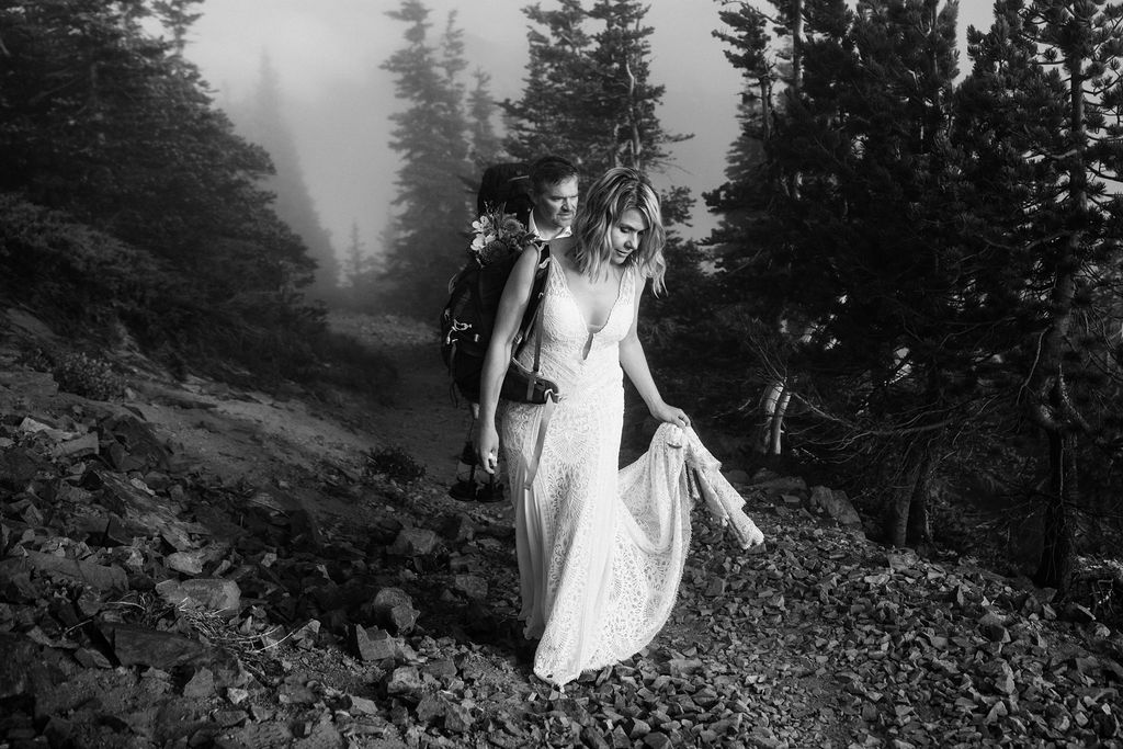 bride and groom walk on dirt path with fog and trees around them during mt rainier elopement