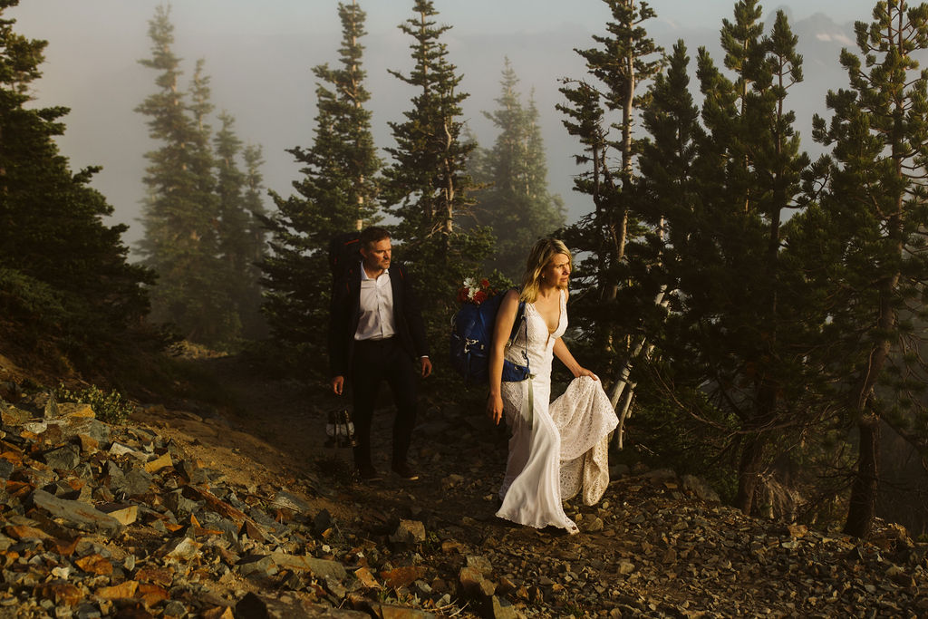 bride and groom walk on dirt path with fog and trees around them during mt rainier elopement