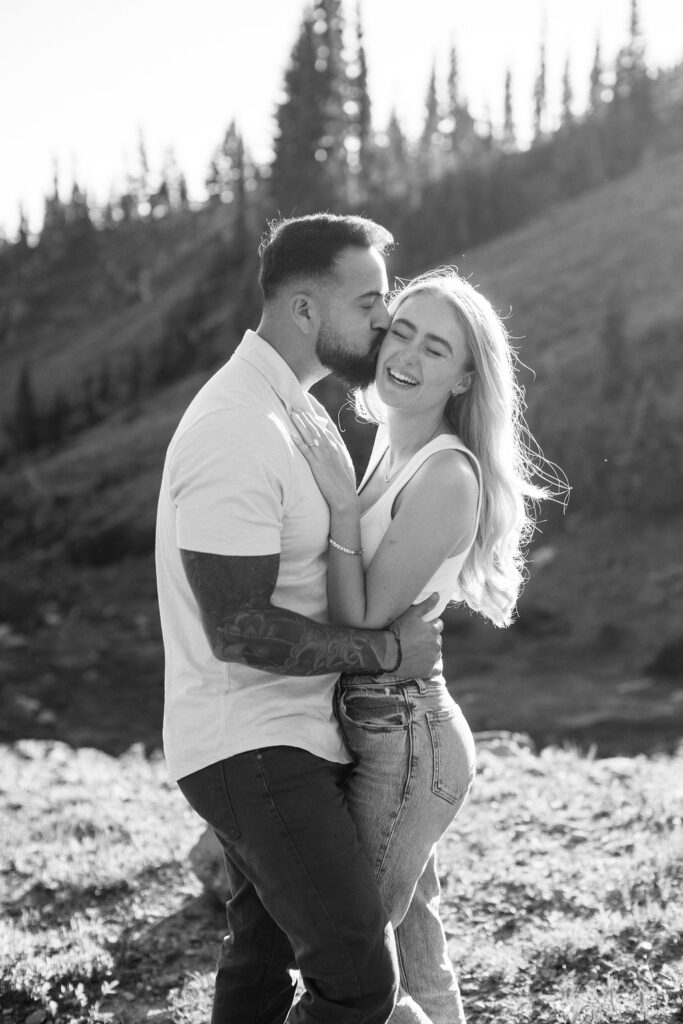 boy kisses girl on the cheek as she smiles at mt rainier engagement session