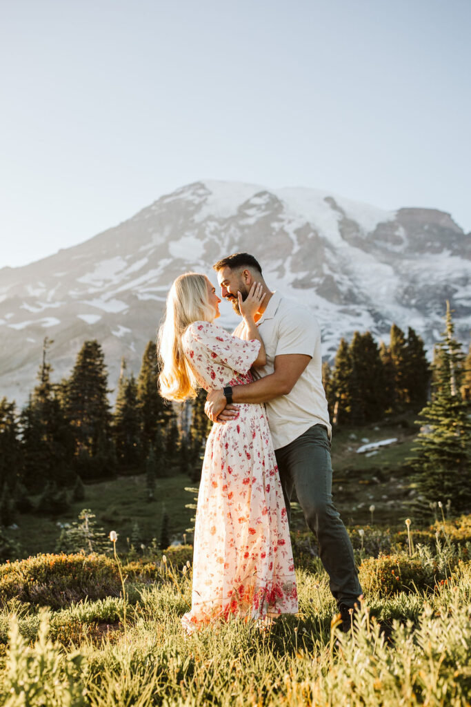 boy and girl snuggle in front of mountain at mt rainier engagement session