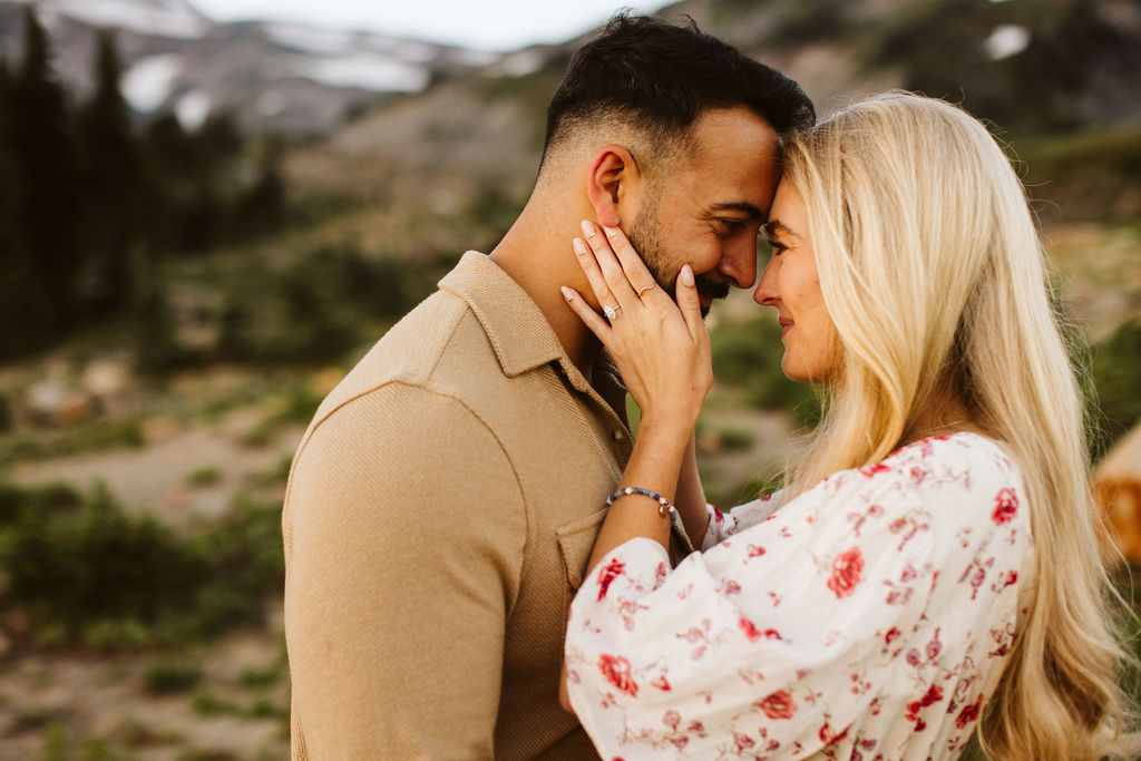 woman holds mans face in her hands at mt rainier engagement session