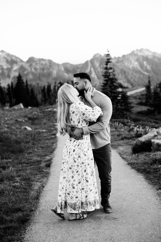 man and woman kiss with mountains in the background