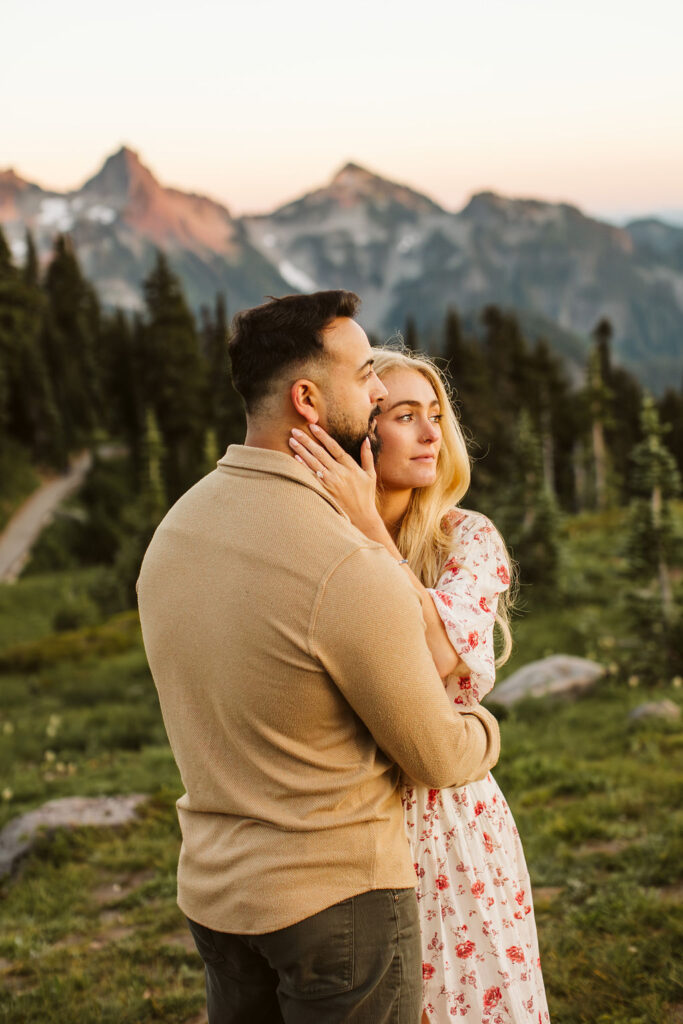 man and woman embrace with mountains behind them