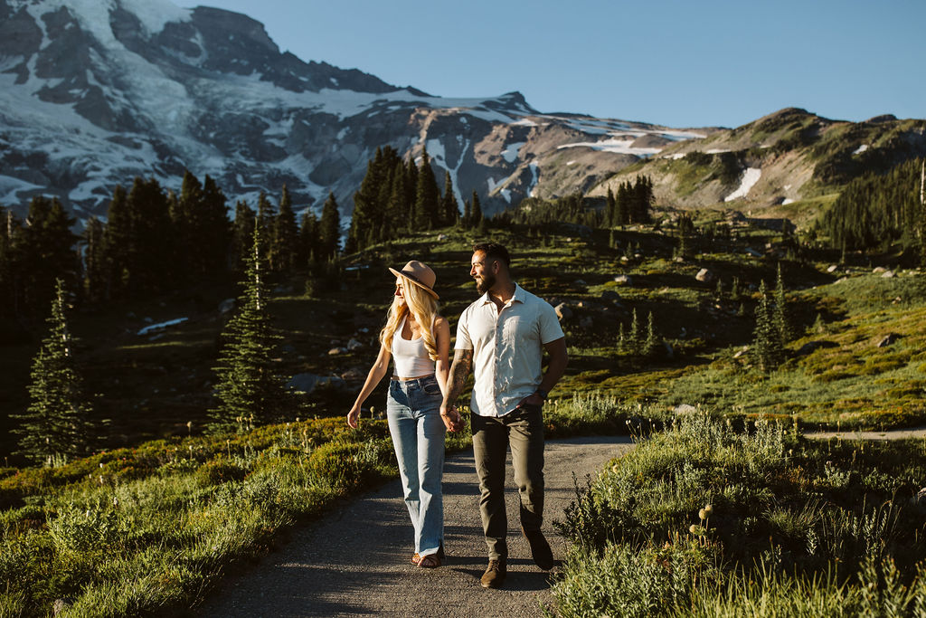 boy and girl walk down gravel path at mt rainier engagement session