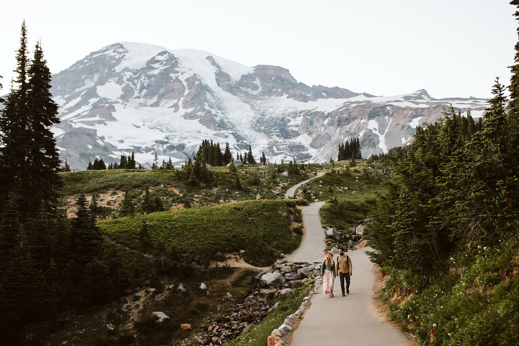 boy and girl walk down a path together at mount rainier engagement session