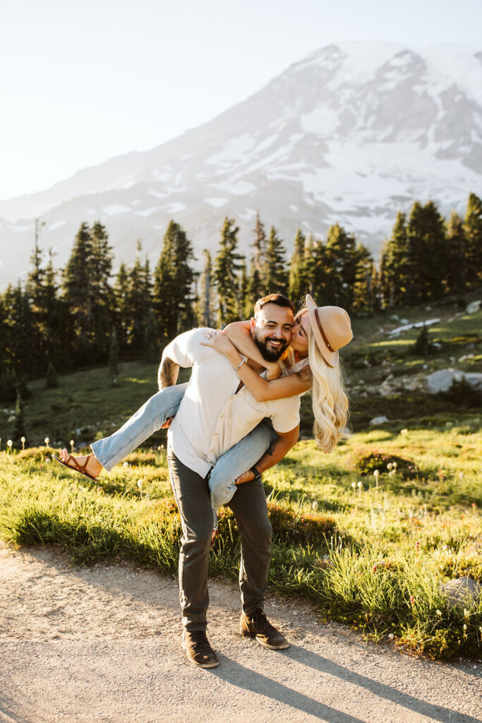 girl is on boys back and kisses him on cheek at mt rainier engagement session