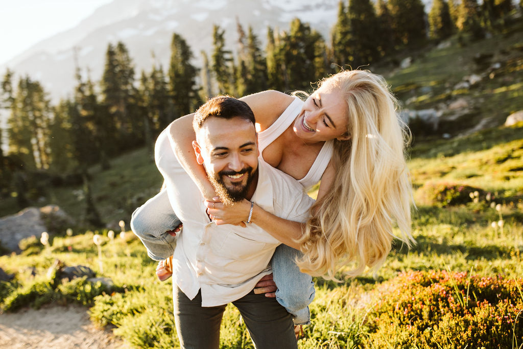 girl is on boys back and is smiling at him at mt rainier engagement session